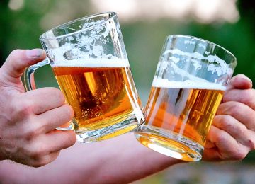 foto de mãos segurando duas canecas de chopp